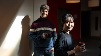 two researchers with coffee mugs looking into the camera