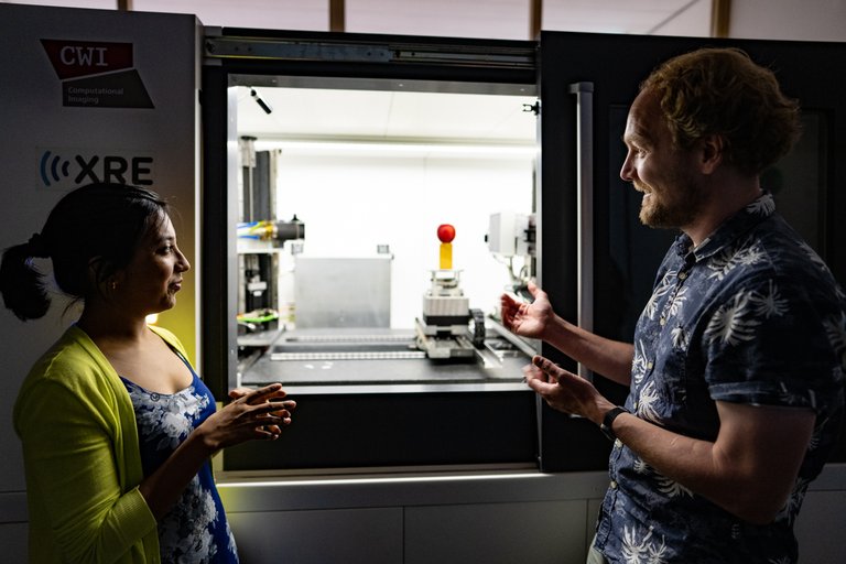 a man and woman in front of the flex ray scanner at cwi