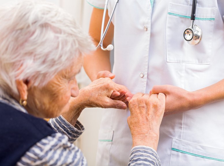 Nurse holds hands of elderly woman